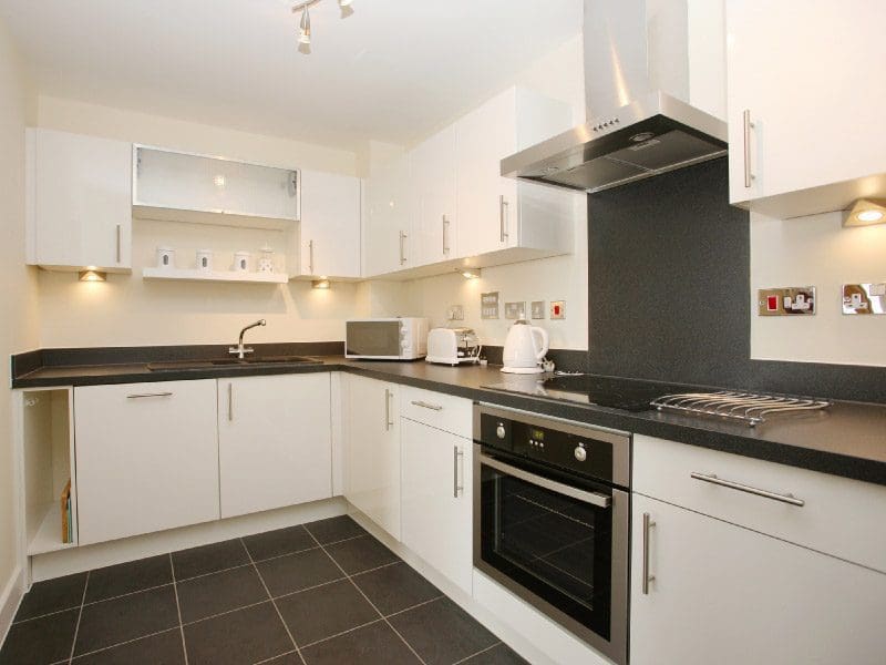 Modern fitted kitchen with white units and a granite worktop